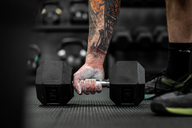 Man picking up dumbbell with RAGE Fitness Chalk Powder on his hands