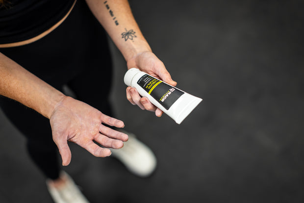 Athlete holding RAGE Fitness Liquid Chalk in hand, showing other callused hand